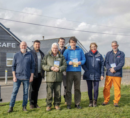 Group of people holding the Coast Path guidebook