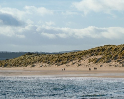 People walking along Beadnell Bay